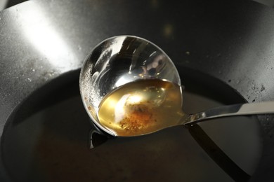 Used cooking oil and ladle in frying pan, closeup