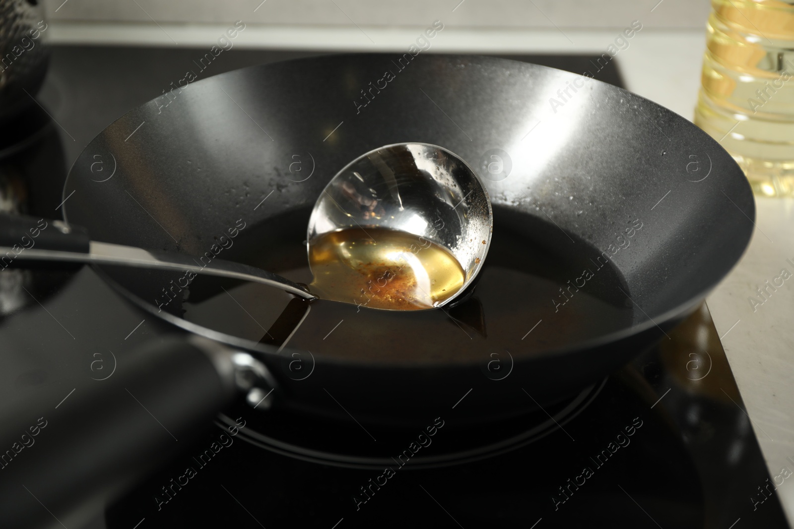 Photo of Used cooking oil and ladle in frying pan on stove, closeup