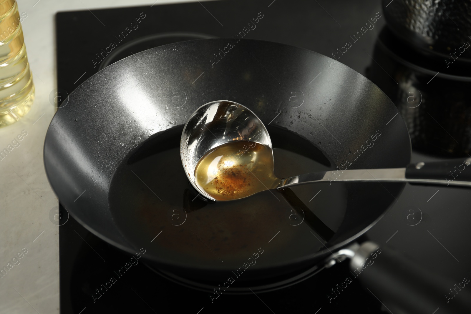 Photo of Used cooking oil and ladle in frying pan on stove