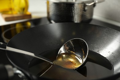 Photo of Used cooking oil and ladle in frying pan on stove, closeup