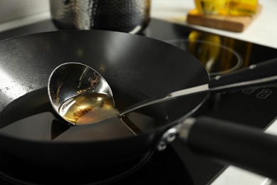 Photo of Used cooking oil and ladle in frying pan on stove, closeup