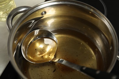 Photo of Used cooking oil and ladle in saucepan on stove, closeup