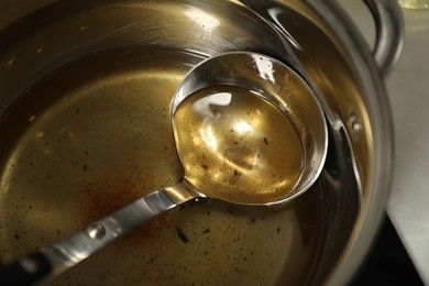 Photo of Used cooking oil and ladle in saucepan on stove, closeup