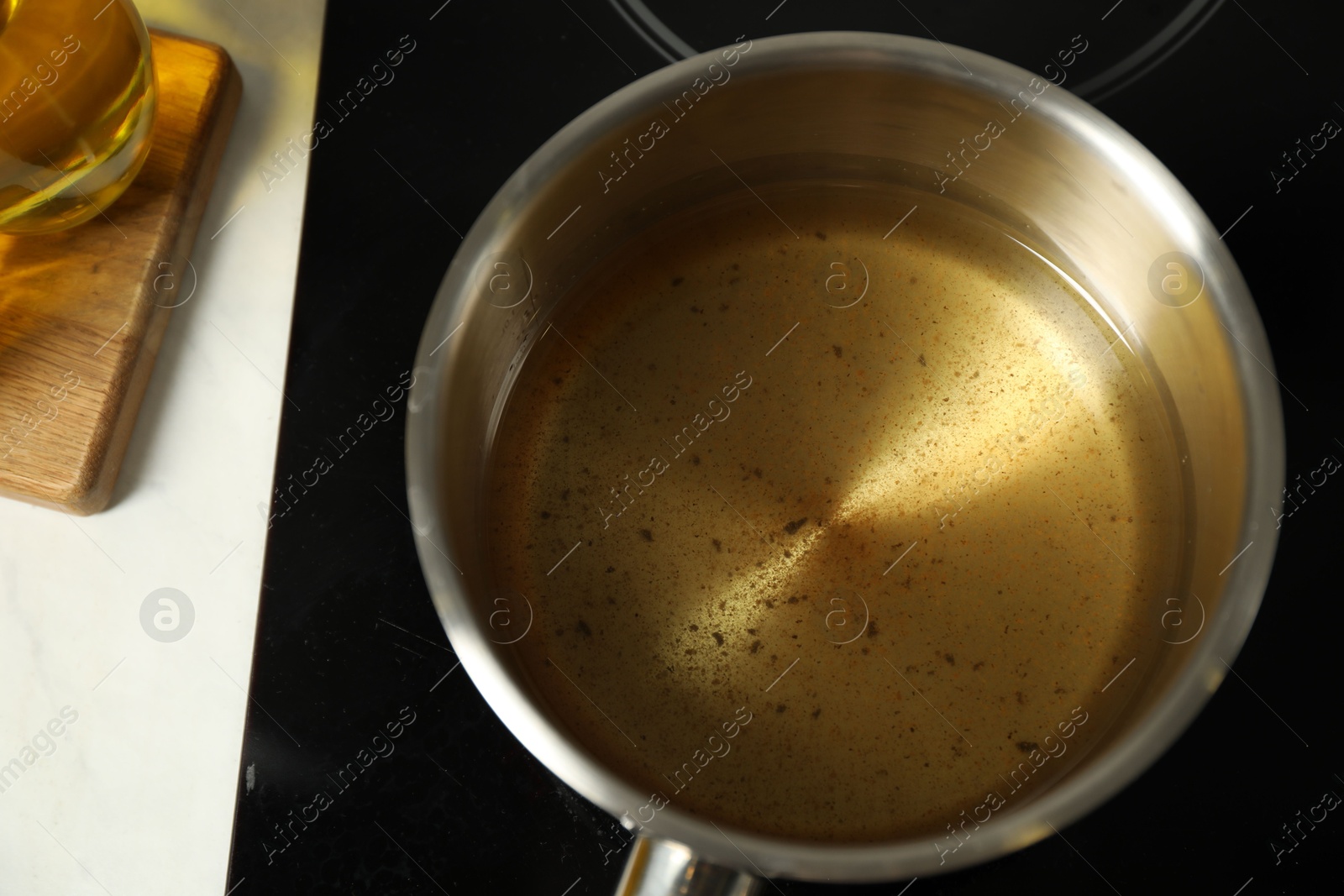 Photo of Used cooking oil in saute pan on stove, above view