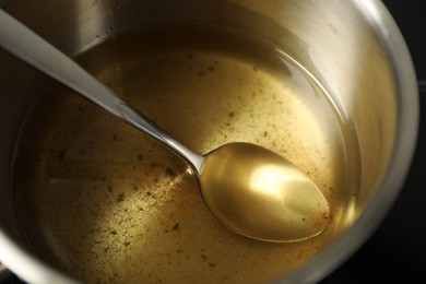 Photo of Used cooking oil and spoon in saute pan, closeup