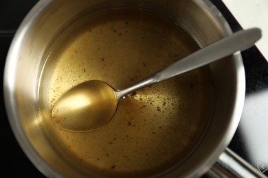 Photo of Used cooking oil and spoon in saute pan, closeup