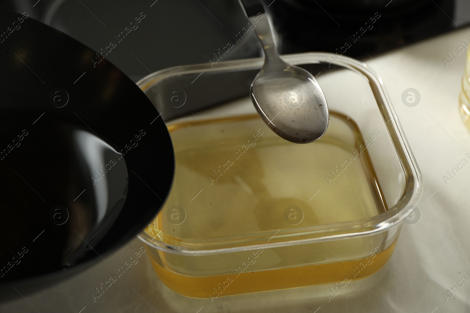 Photo of Pouring used cooking oil at white countertop, closeup