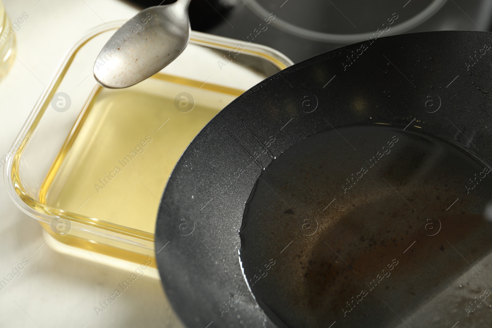 Photo of Pouring used cooking oil at white countertop, closeup