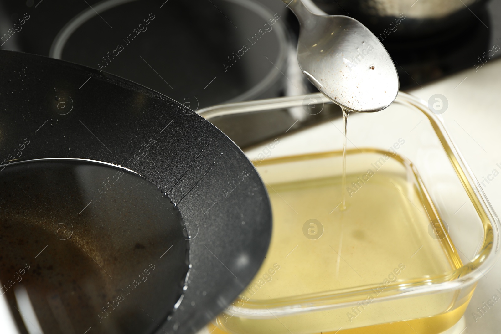 Photo of Pouring used cooking oil at white countertop, closeup