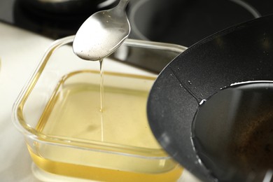 Photo of Pouring used cooking oil at white countertop, closeup