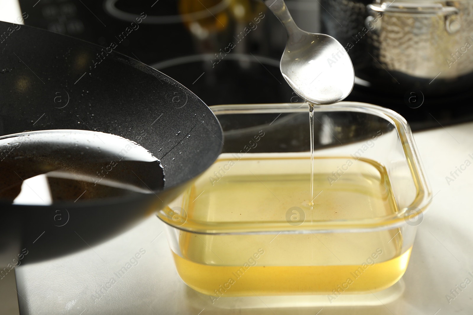 Photo of Pouring used cooking oil at white countertop, closeup