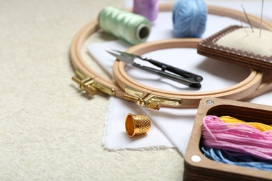 Photo of Embroidery. Different sewing accessories on beige textured table, closeup. Space for text