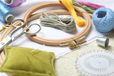 Photo of Embroidery. Different sewing accessories on beige textured table, closeup