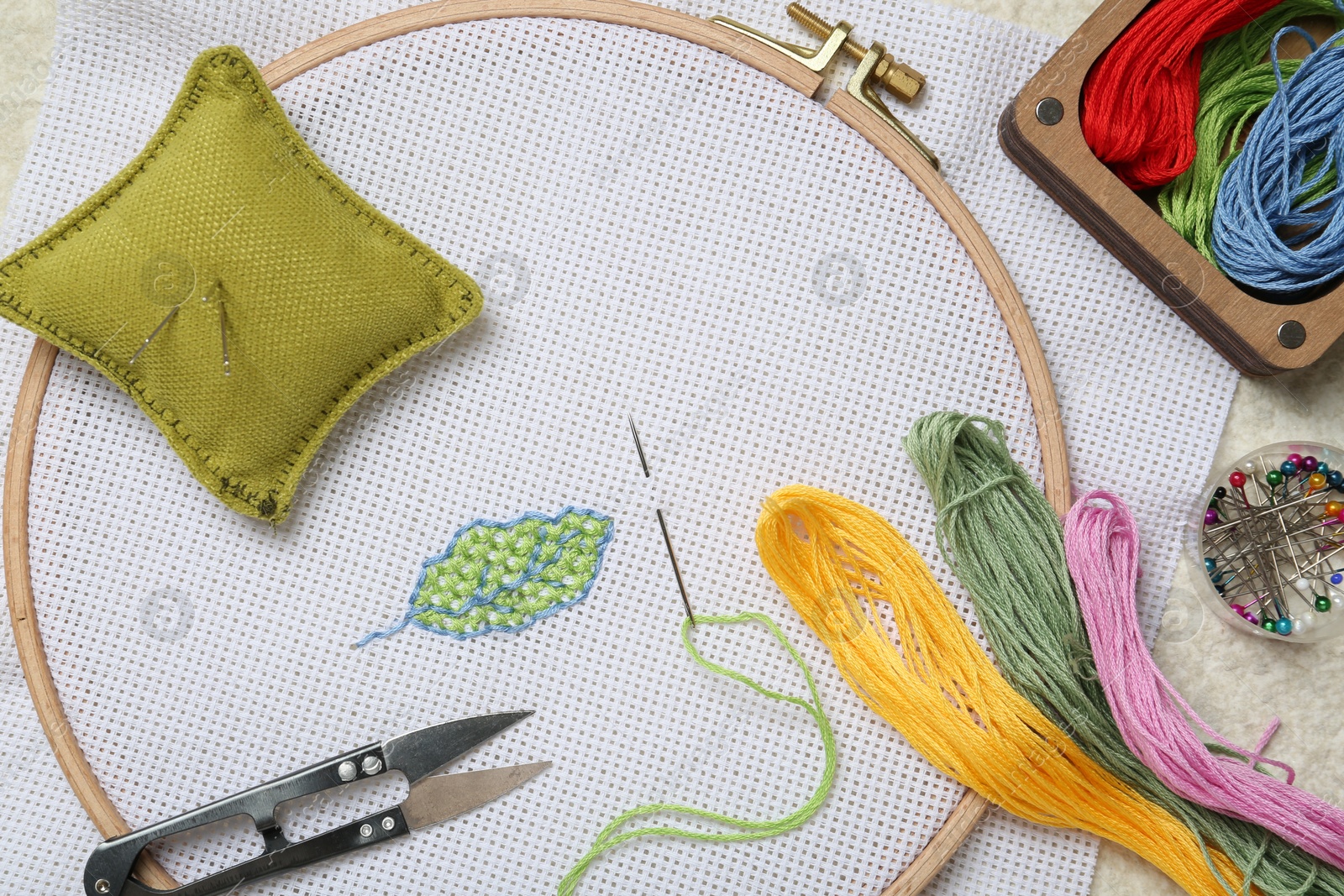 Photo of Embroidery and different sewing accessories on table, flat lay