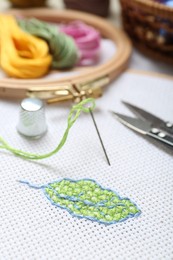 Photo of Embroidery and different sewing accessories on table, closeup