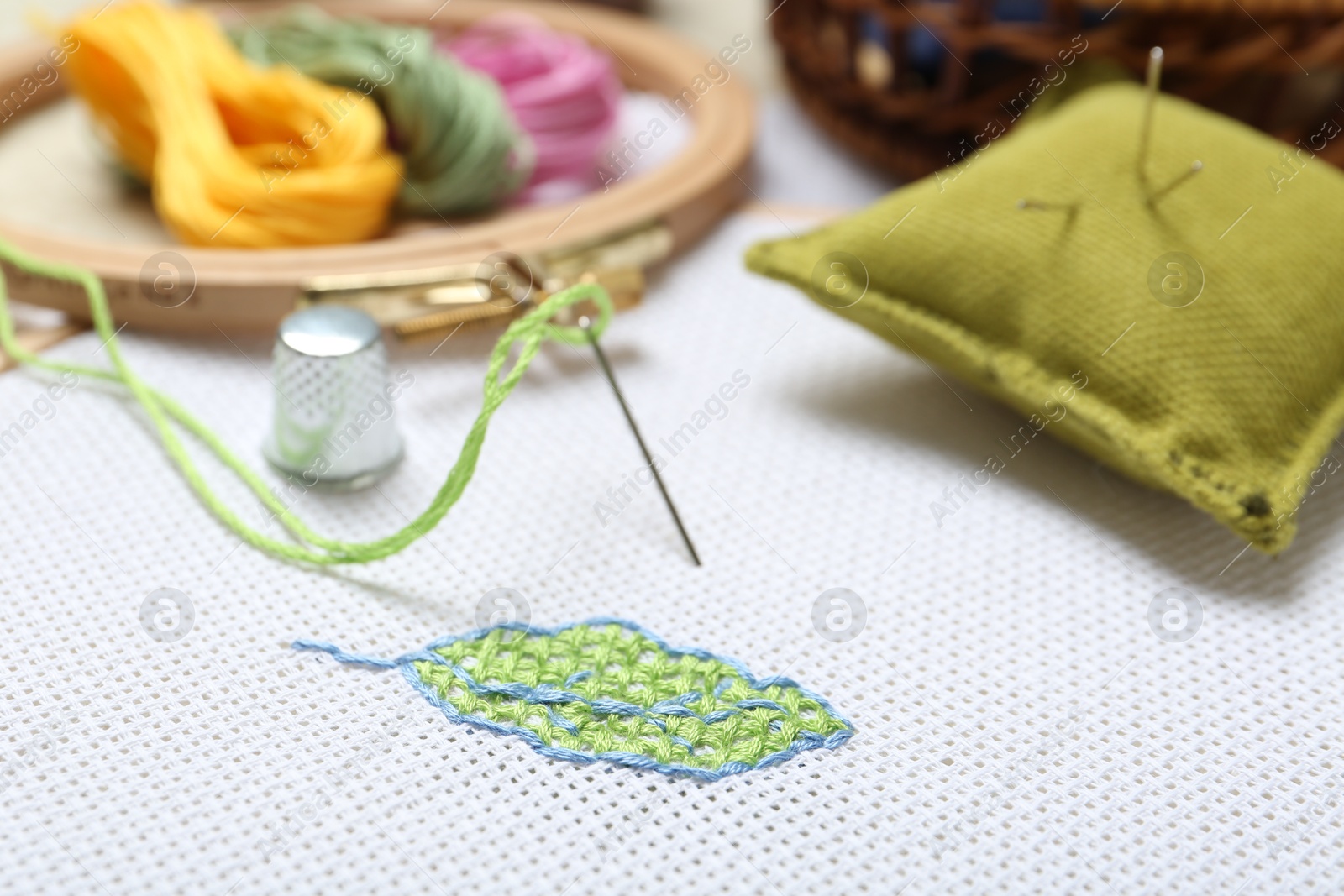 Photo of Embroidery and different sewing accessories on table, closeup