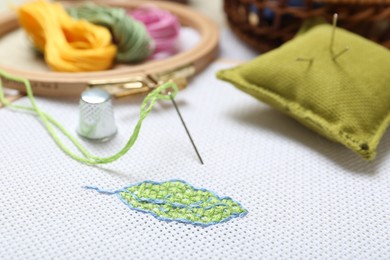 Embroidery and different sewing accessories on table, closeup