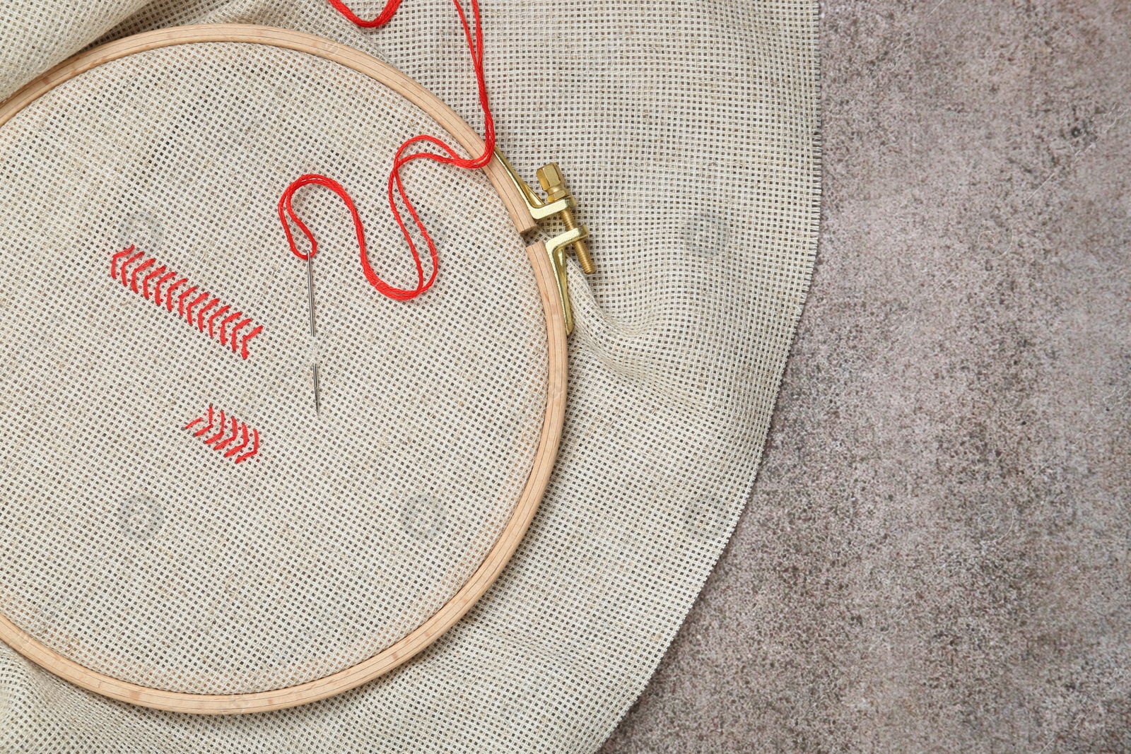 Photo of Canvas with embroidery in hoop on grey table, top view. Space for text