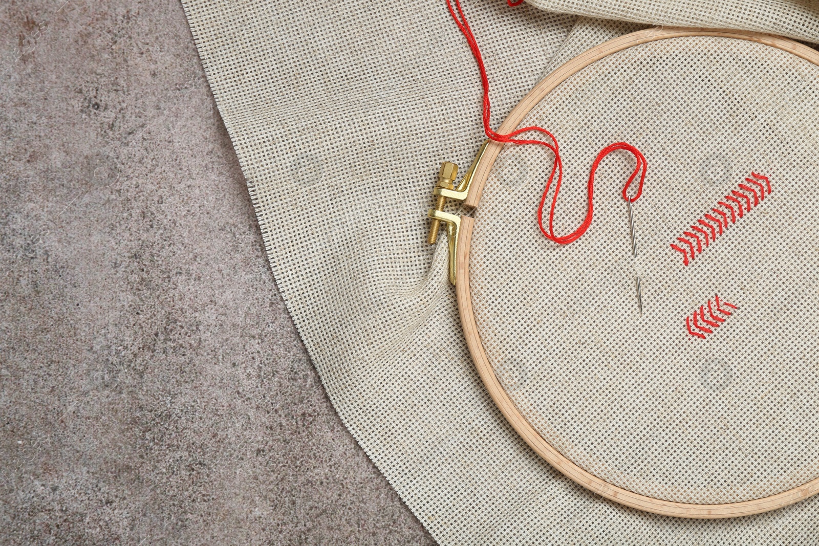 Photo of Canvas with embroidery in hoop on grey table, top view. Space for text