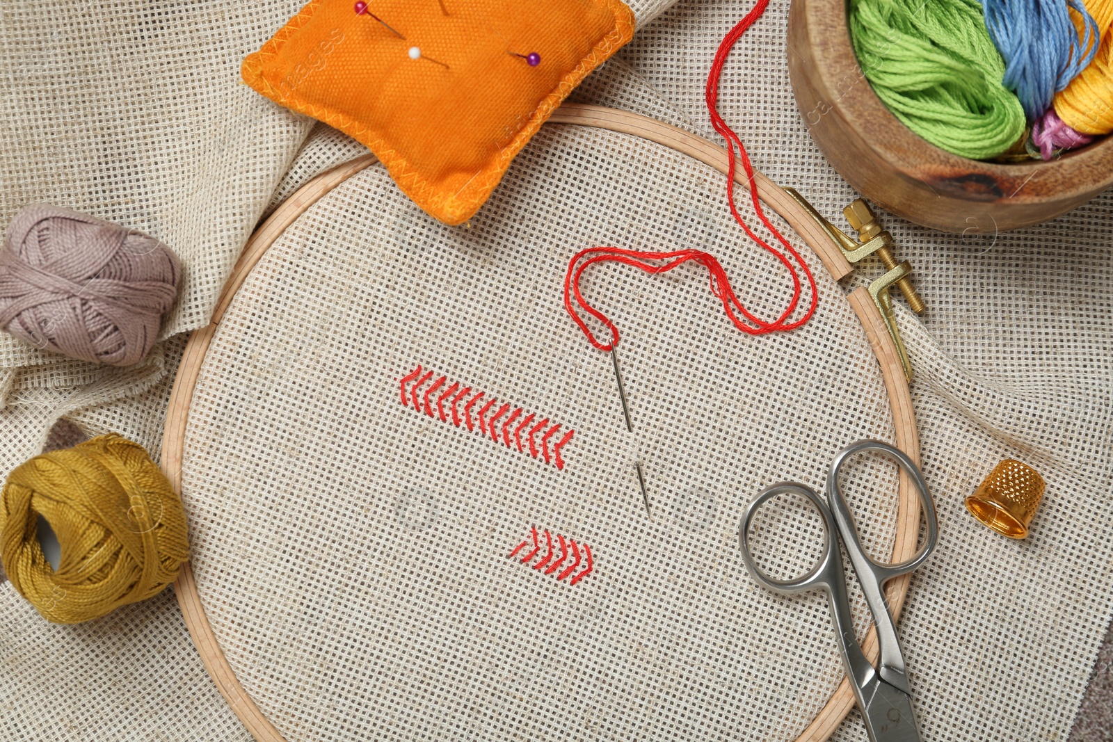 Photo of Embroidery and different sewing accessories on table, flat lay