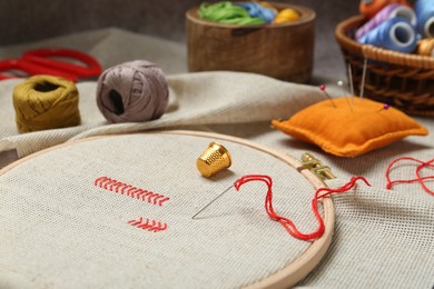 Photo of Embroidery and different sewing accessories on table, closeup