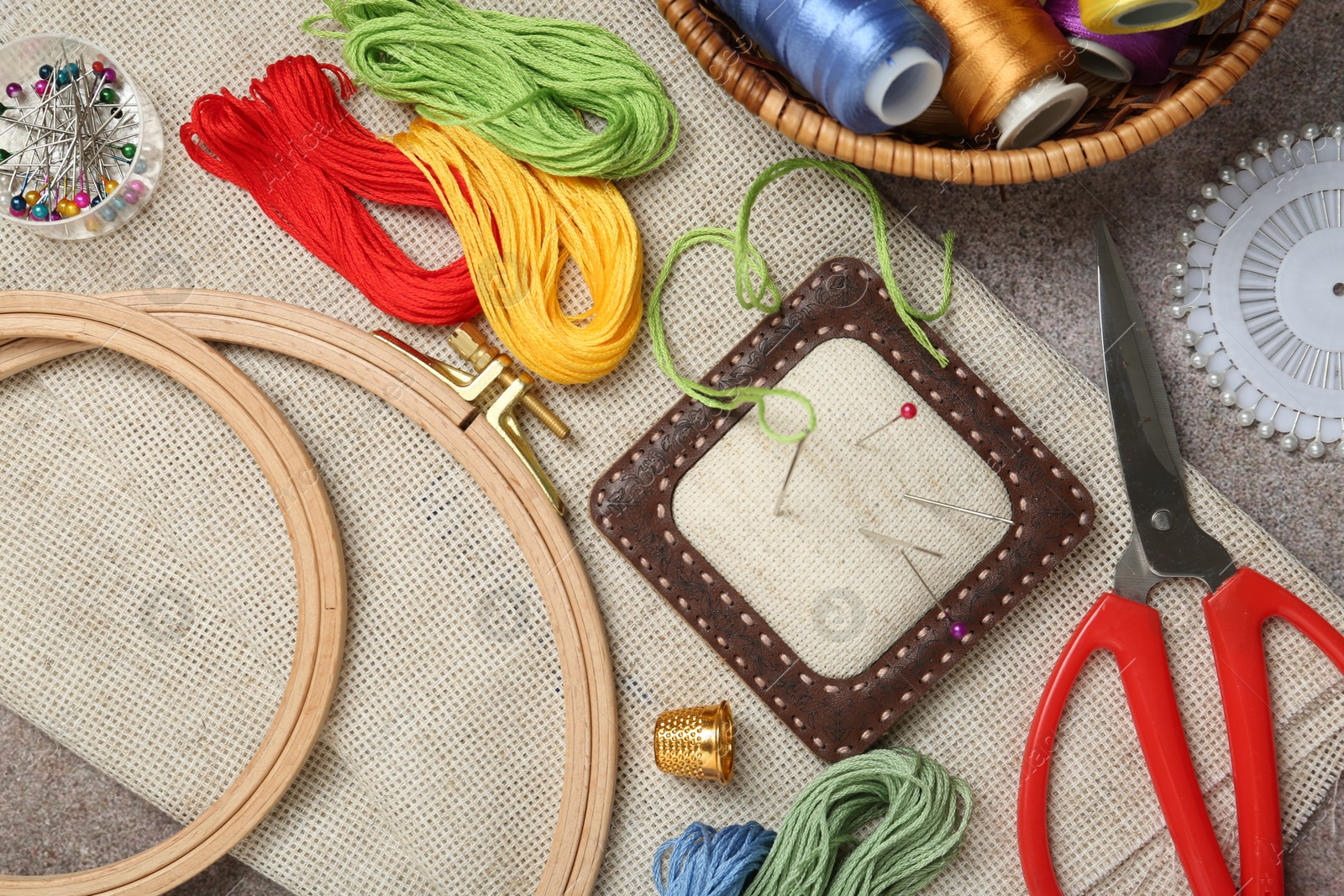 Photo of Embroidery. Different sewing accessories on grey table, flat lay