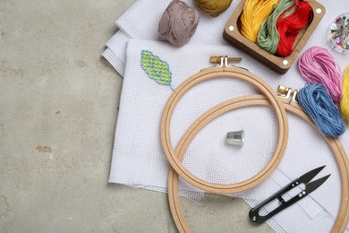 Photo of Embroidery and different sewing accessories on grey table, flat lay. Space for text