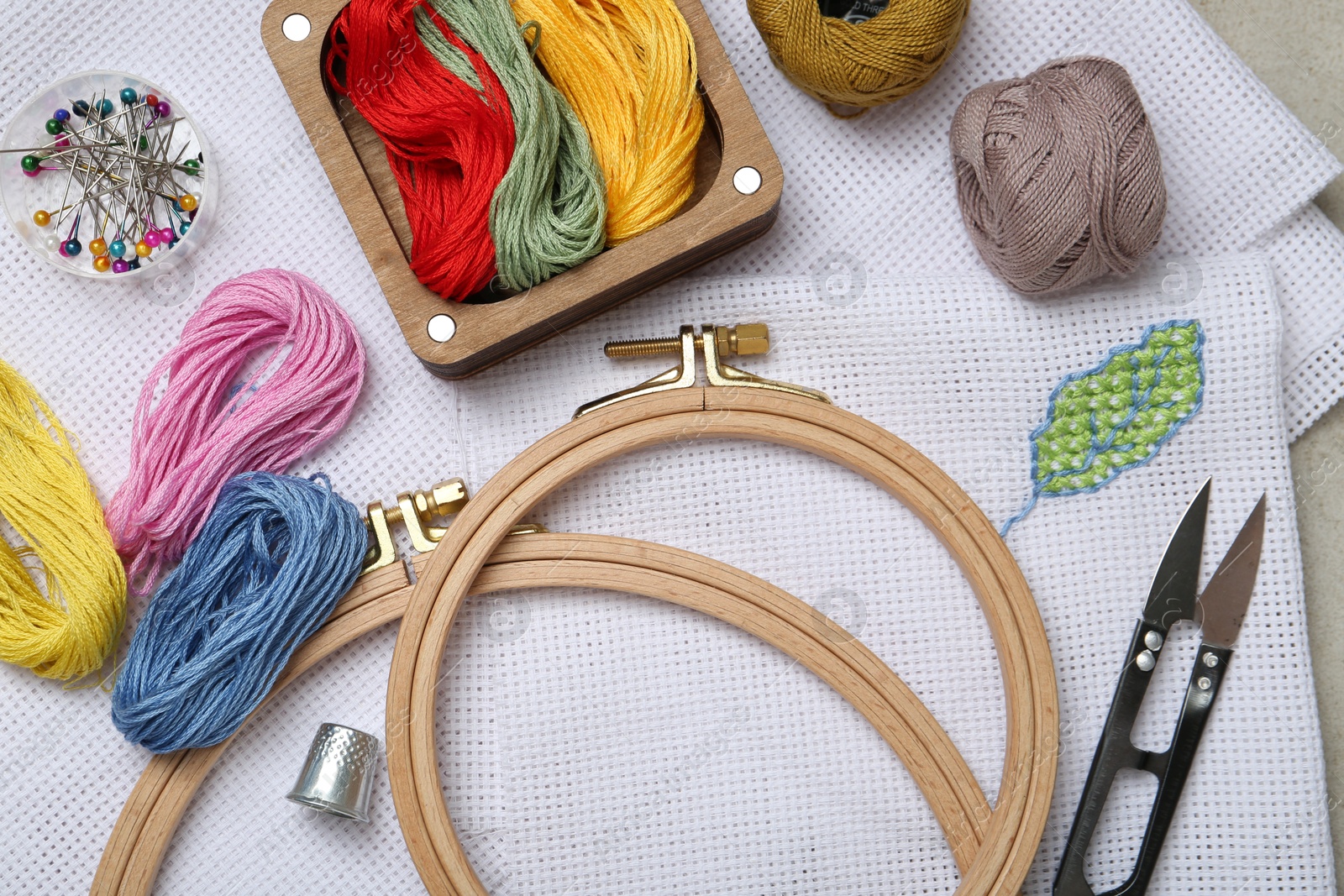 Photo of Embroidery and different sewing accessories on table, flat lay