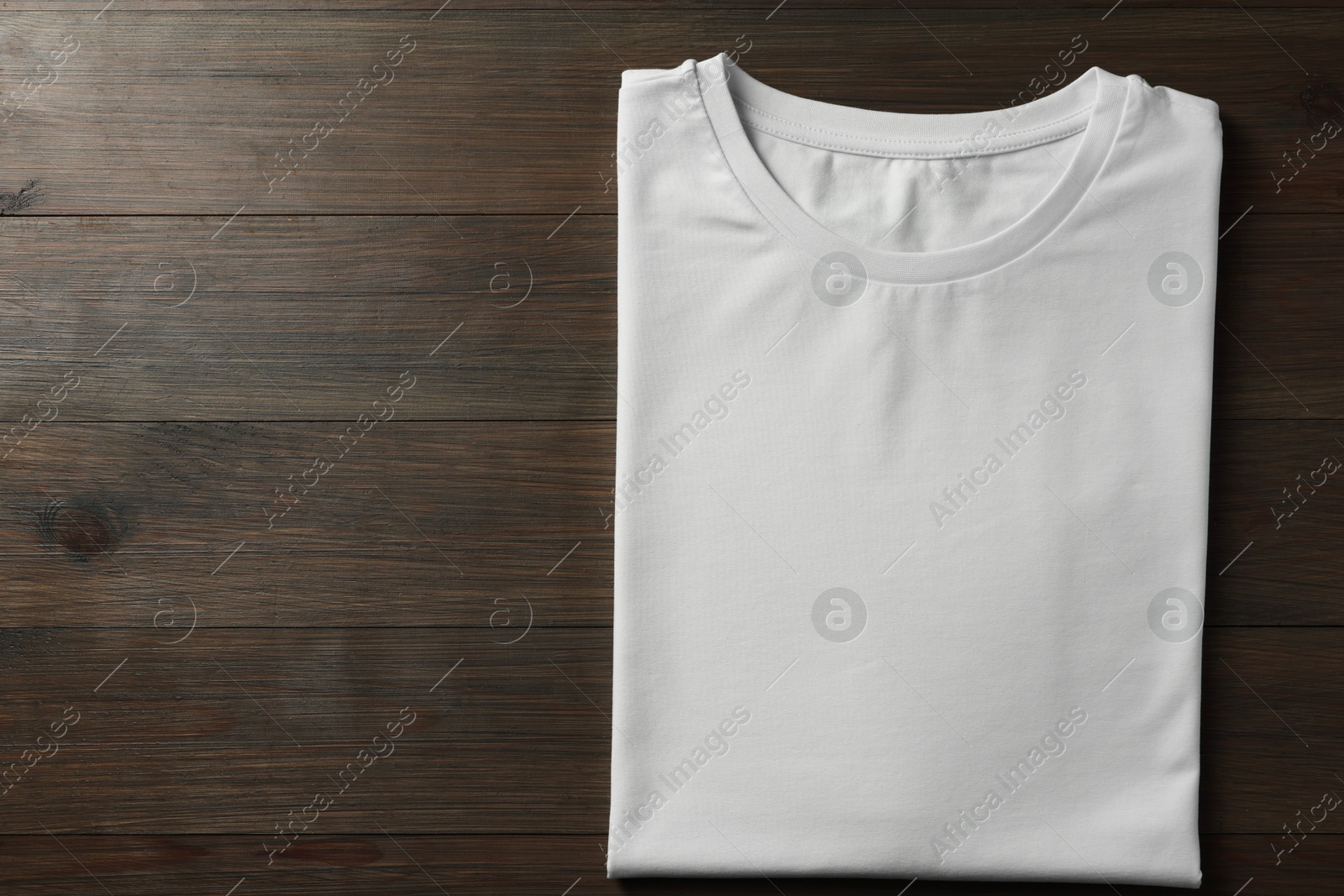 Photo of Blank white t-shirt on wooden background, top view. Mockup for design