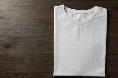 Blank white t-shirt on wooden background, top view. Mockup for design