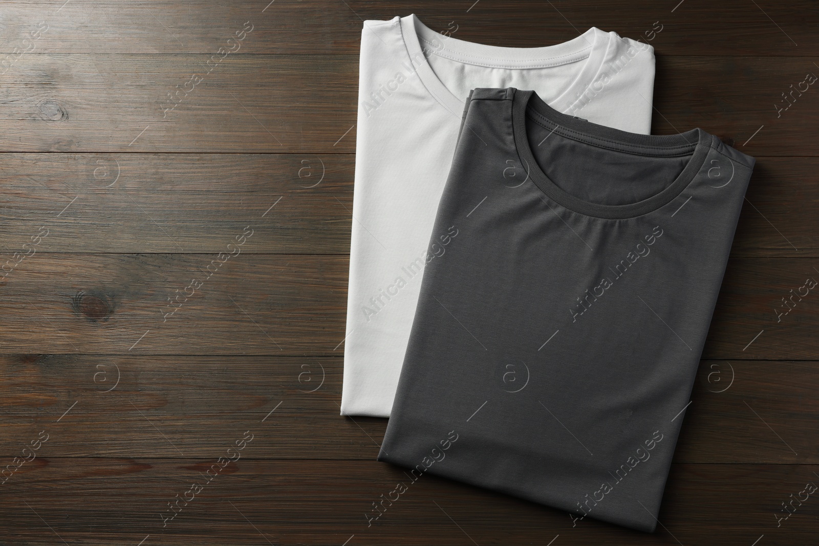 Photo of Different blank t-shirts on wooden background, top view. Mockup for design