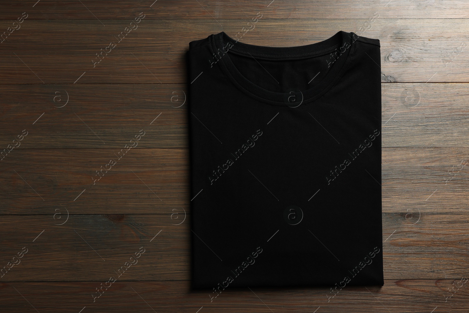 Photo of Blank black t-shirt on wooden background, top view. Mockup for design