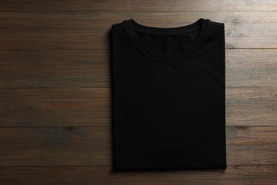 Photo of Blank black t-shirt on wooden background, top view. Mockup for design