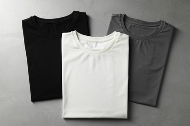 Photo of Different blank t-shirts on grey background, top view. Mockup for design