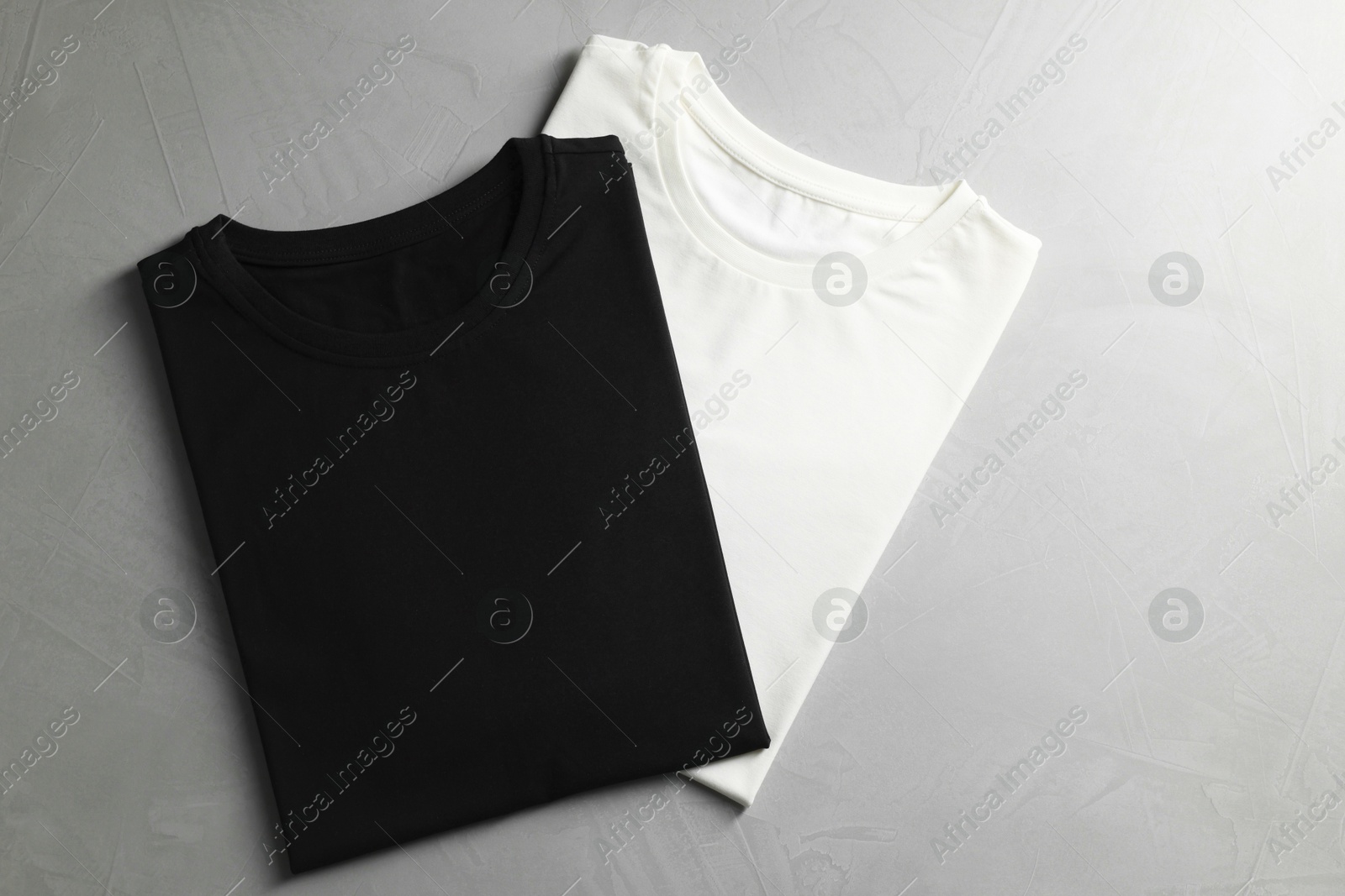 Photo of Different blank t-shirts on grey background, top view. Mockup for design