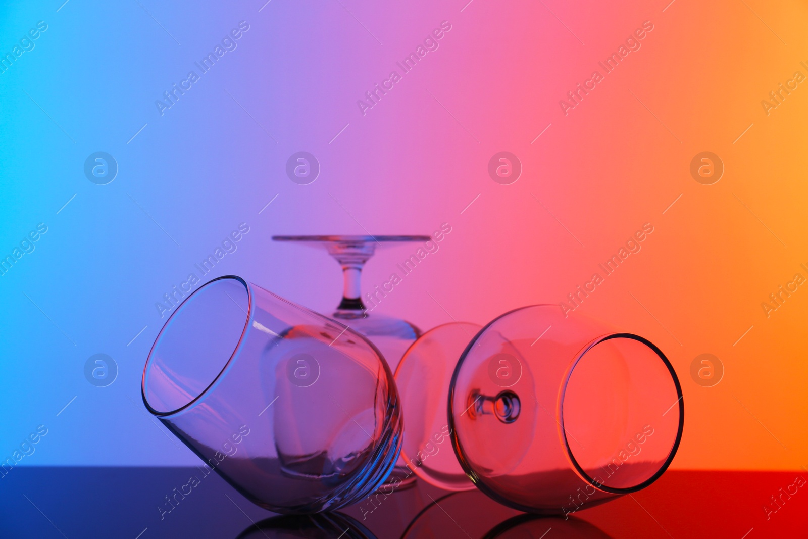 Photo of Empty glasses on table against color background