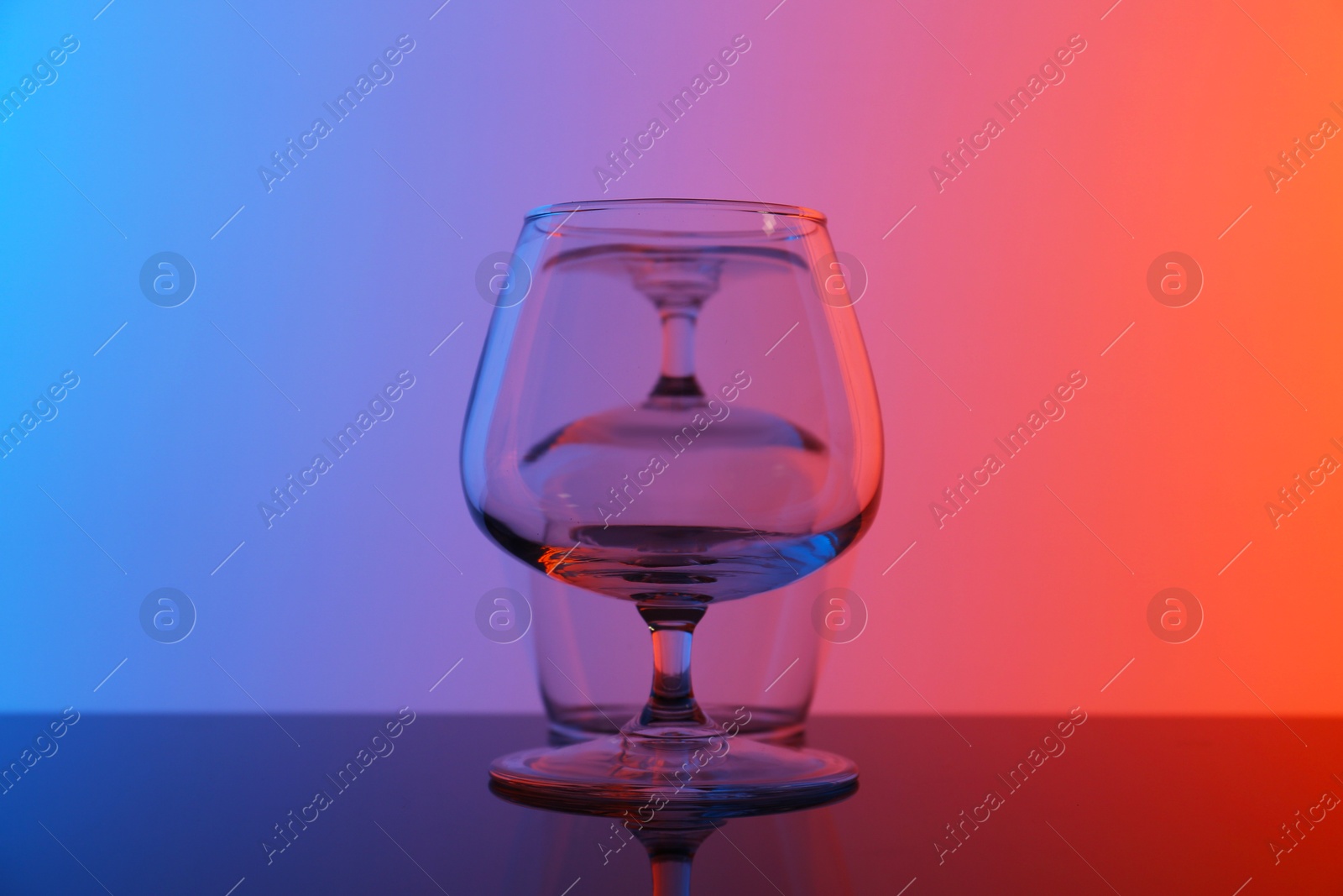 Photo of Empty glasses on table against color background