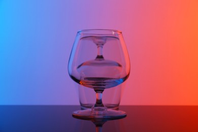 Photo of Empty glasses on table against color background