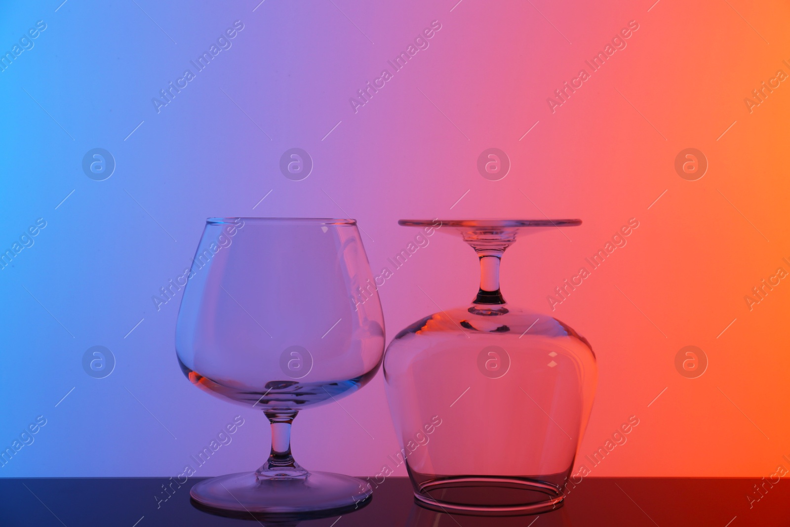 Photo of Empty glasses on table against color background