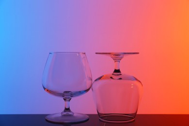 Photo of Empty glasses on table against color background