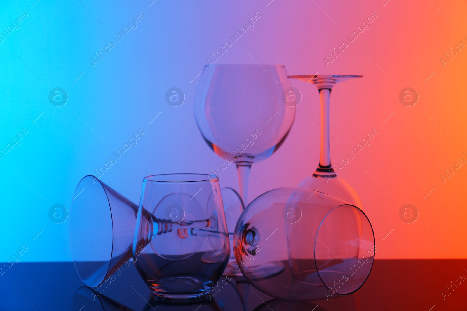 Photo of Empty glasses on table against color background