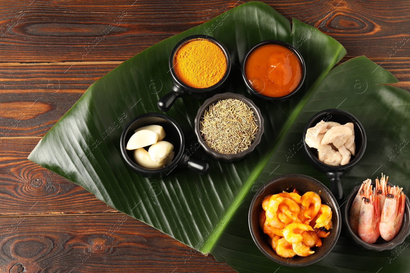 Photo of Cut banana leaf with different food, spices and sauce on wooden table, top view