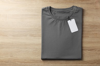 Photo of One blank t-shirt on wooden background, top view. Mockup for design