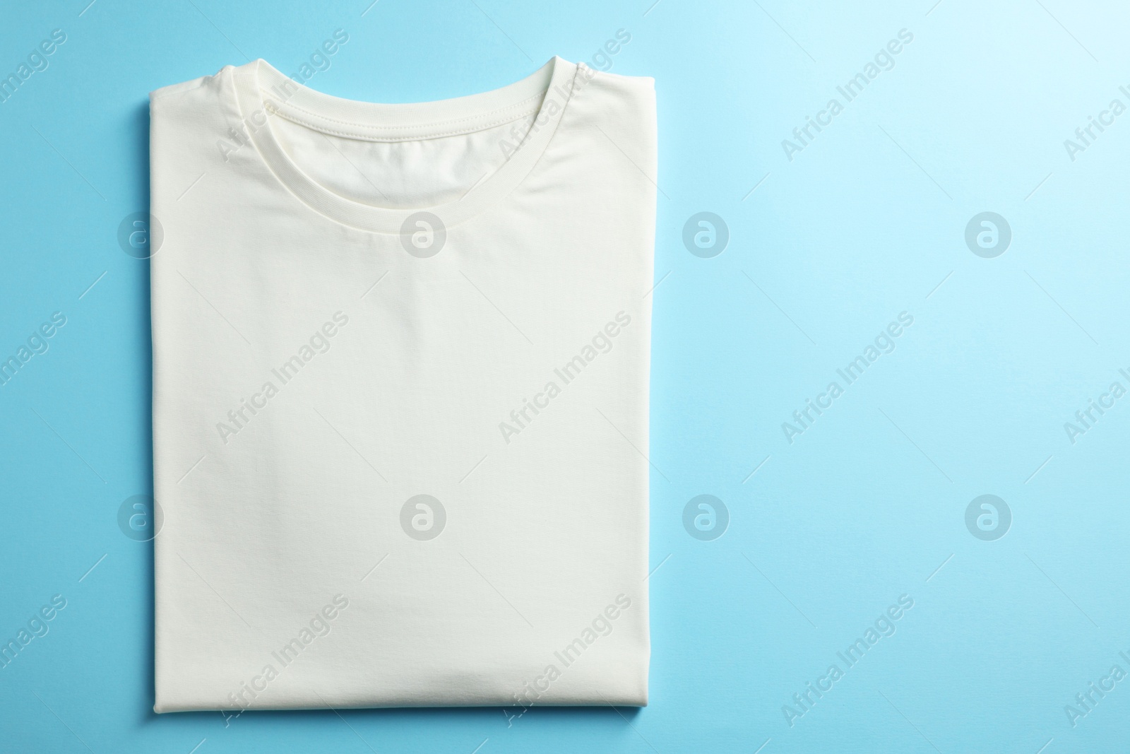 Photo of One blank t-shirt on light blue background, top view. Mockup for design