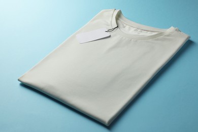 Photo of One blank t-shirt on light blue background, closeup. Mockup for design