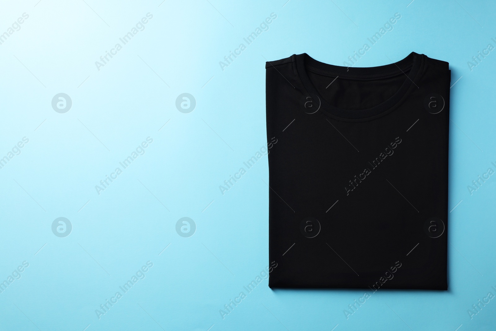 Photo of One blank t-shirt on light blue background, top view. Mockup for design