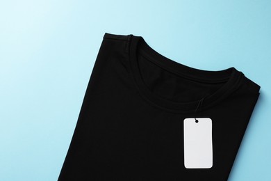 Photo of One blank t-shirt on light blue background, top view. Mockup for design