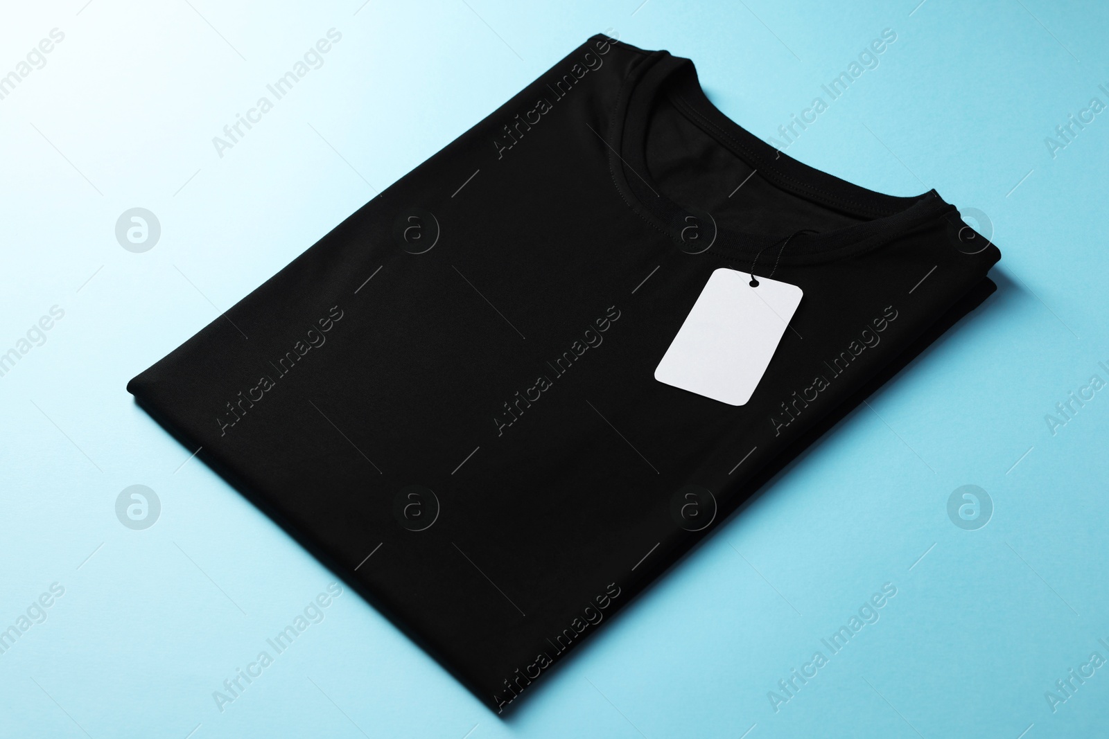 Photo of One blank t-shirt on light blue background, closeup. Mockup for design