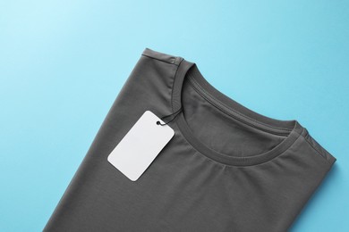 Photo of One blank t-shirt on light blue background, top view. Mockup for design