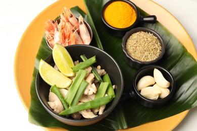 Photo of Piece of banana leaf with different food and spices on white table, closeup. Healthy eco serving